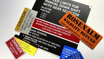 Custom-printed aluminum safety nameplates with caution and warning messages for machinery, made in the Bay Area.