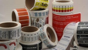 Rolls of durable industrial labels with safety and compliance text, manufactured near San Jose, CA for OEM and equipment labeling.