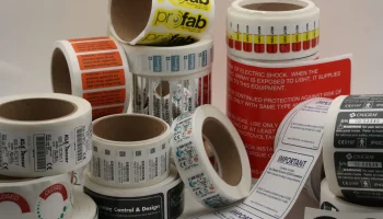 Rolls of durable industrial labels with safety and compliance text for OEM equipment labeling.